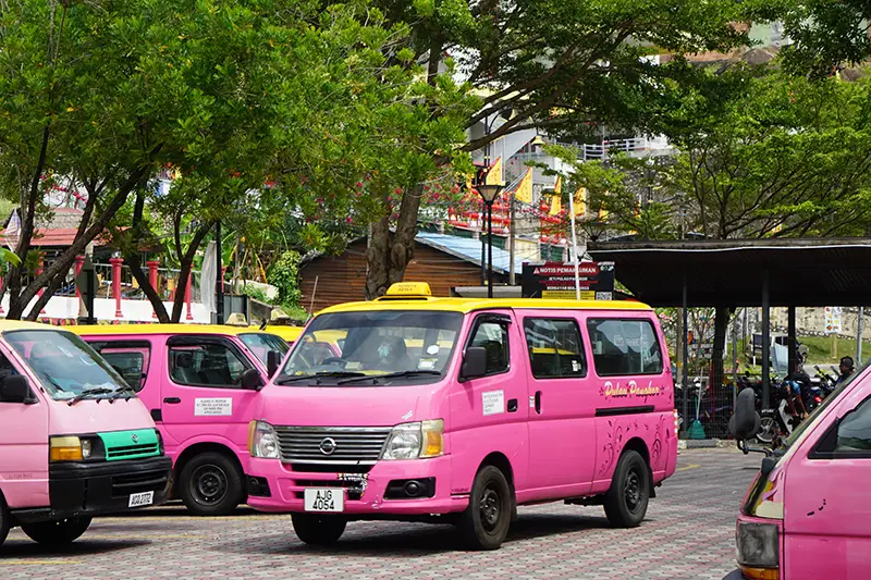Pink taxi vans waiting at a taxi stand on Pangkor Island, the main mode of transportation for getting around the island.