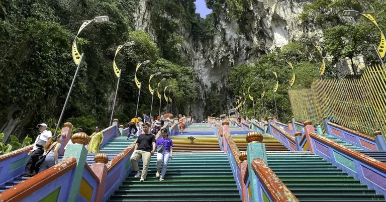 Tourists climbing the colorful 272 rainbow Batu Caves staircase leading to upper caves
