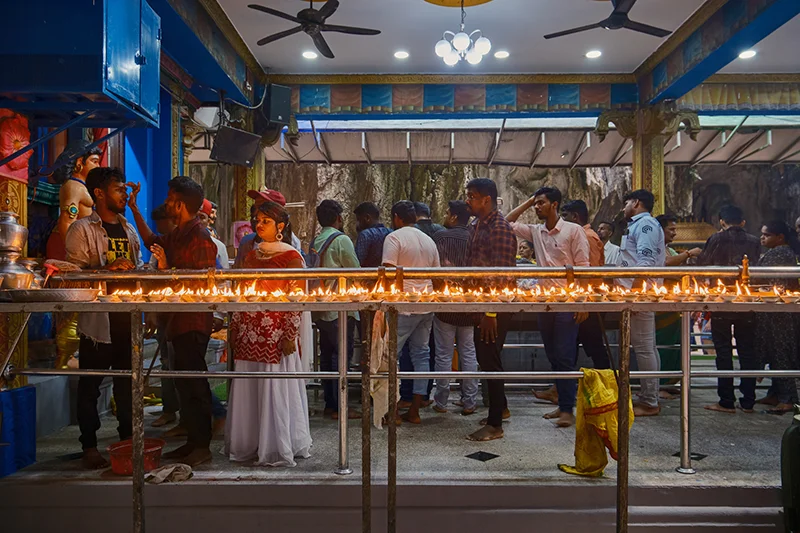 Hindu devotees performing a traditional ceremony with oil lamps inside the Batu Caves temple during a Batu Caves visit in Malaysia