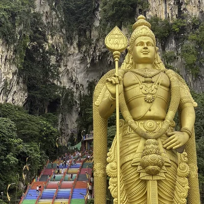 Golden Lord Murugan statue at Batu Caves with colorful staircase in the background, a top tourist attraction near Kuala Lumpur