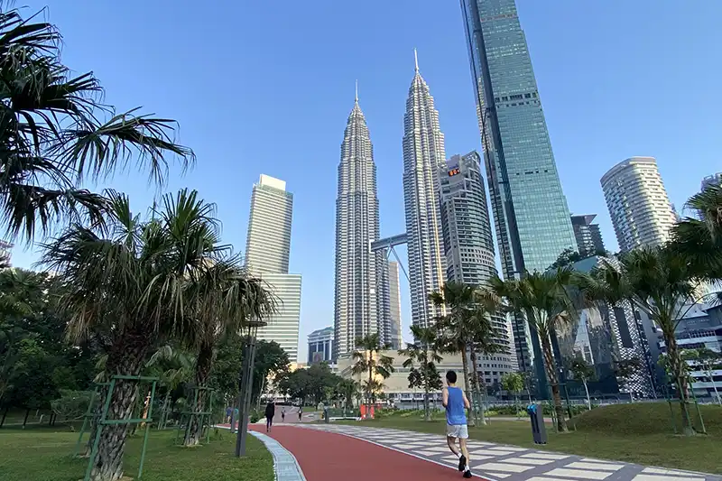 Morning joggers at KLCC Park with Petronas Twin Towers view — one of the best things to do in Kuala Lumpur.
