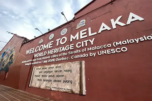 Welcome to Malacca sign displayed on a red heritage building wall