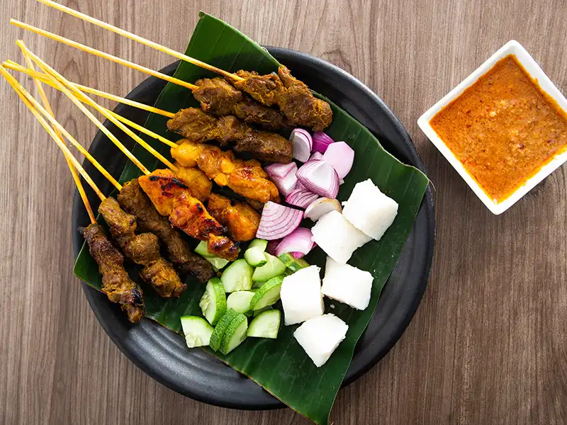 Satay skewers with peanut sauce served on banana leaf, a popular Malaysian street food in Kuala Lumpur