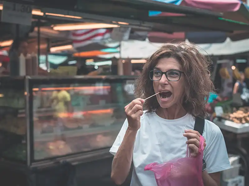 Foreign tourist trying Malaysian street food at a night market in Kuala Lumpur