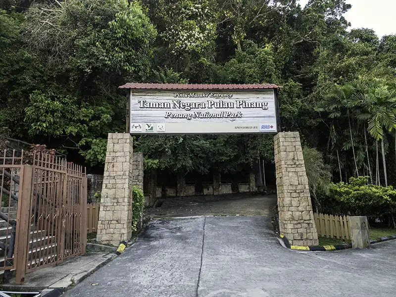 Entrance sign of Penang National Park surrounded by tropical rainforest