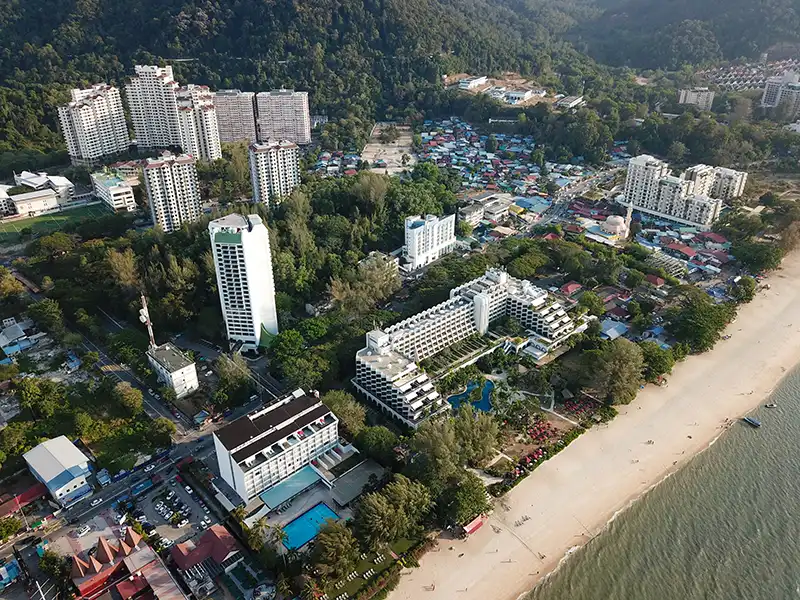 Aerial view of Teluk Bahang beach area in Penang with coastline, hills, and resorts