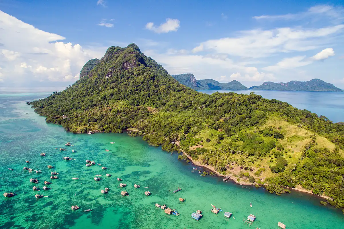 Tropical island landscape at Mabul–Dulang area in Malaysian Borneo with clear water and forested hills